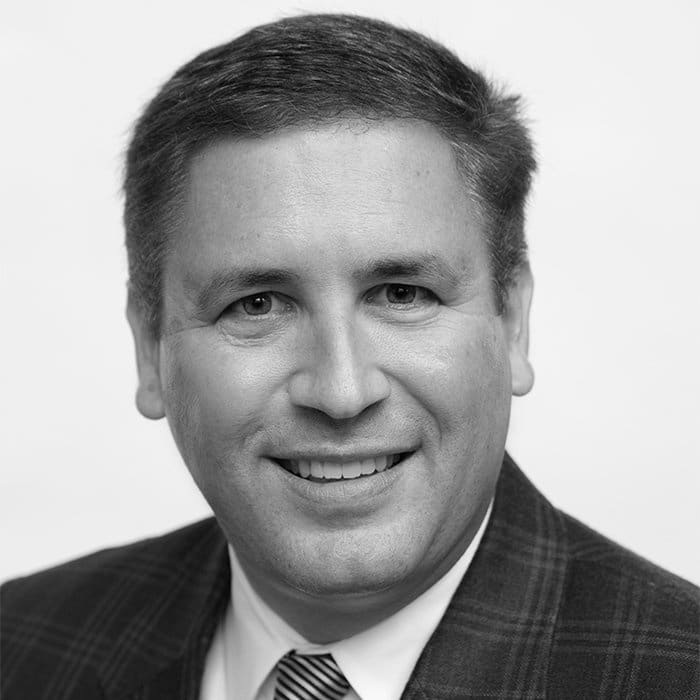 a man wearing a suit and tie smiling and looking at the camera