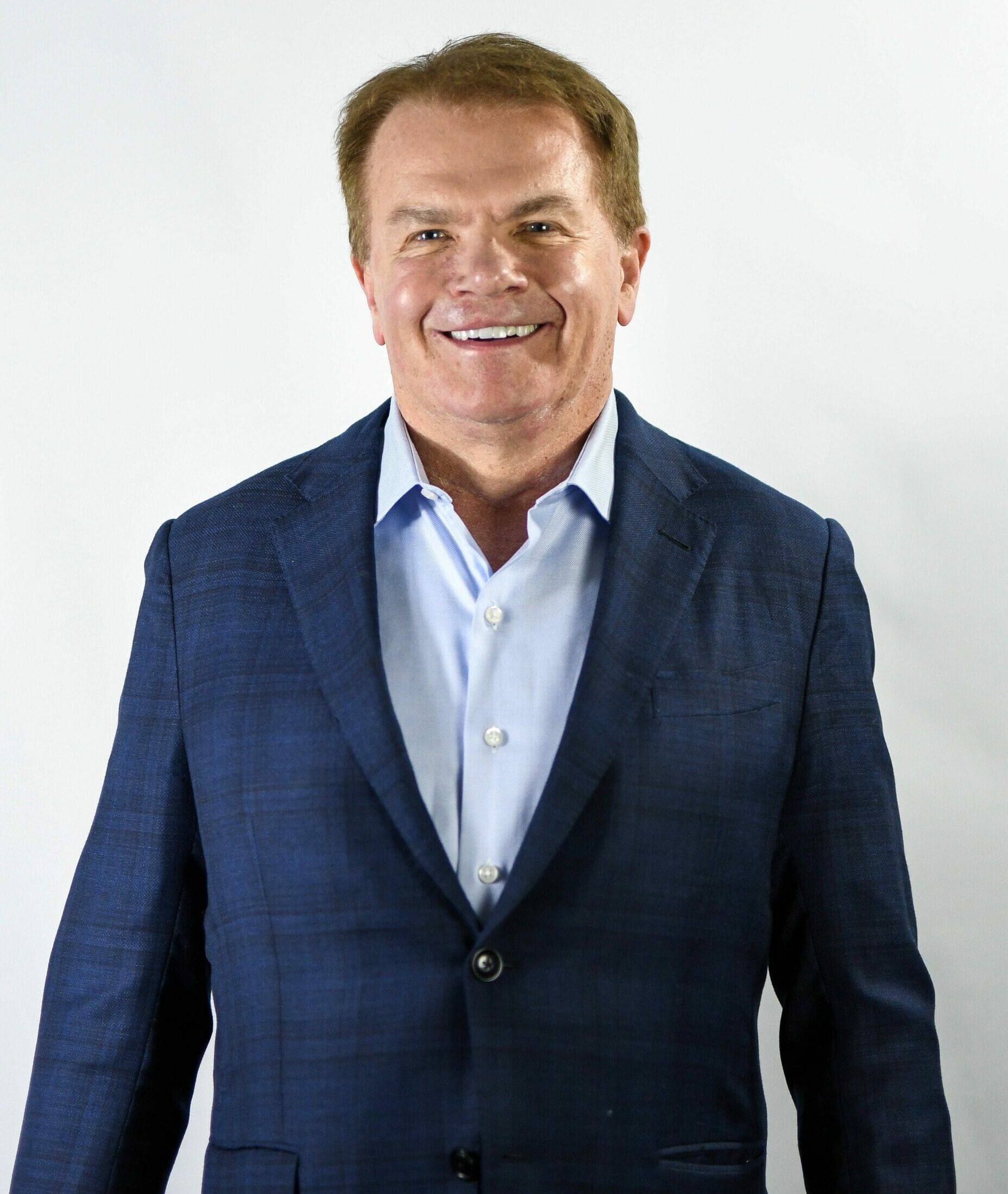 Gene Hallman wearing a suit and tie smiling at the camera